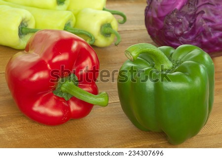 Red and Green bell pepper on wooden table with sweet pepper and red cabbage background
