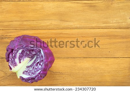 Quarter section of purple round cabbage over wooden background