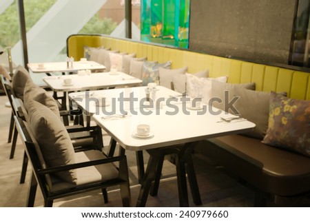 Abstract blurry restaurant with blurry green large tree visible outside windows in background