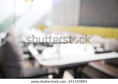 Abstract blurry restaurant with blurry green large tree visible outside windows in background