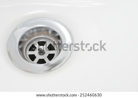 Closeup of stainless steel drain of white washbasin background