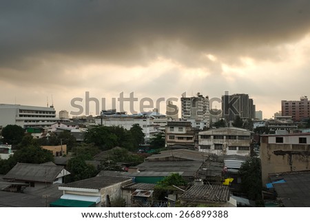 Sun light shine through dark cloud with high density resident cityscape of Bangkok view