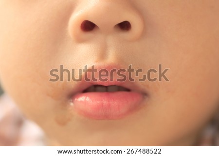 Abstract shallow DOF closeup of toddler face showing nostril and mouth full of chocolate milk stain