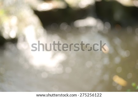 Abstract blurry small waterfall in park background with bright round bokeh