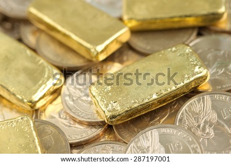 Stack of actual smallest gold bar commonly sold in Thailand over pile of dollar coins. Each bar is 96.5% purity gold which is roughly equal to 99.5% purity 2.527 troy ounce.