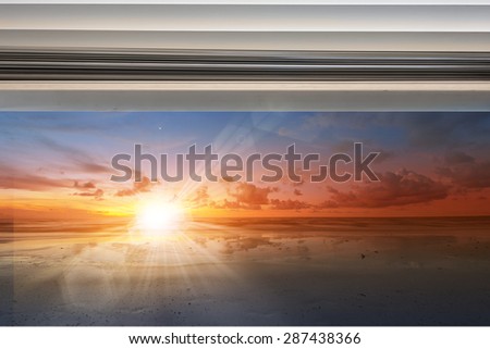 Sunshine over seascape through window with rolled up curtain