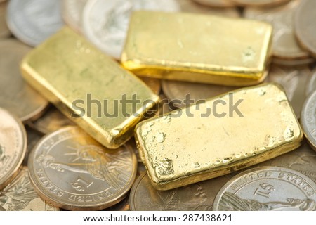 Stack of actual smallest gold bar commonly sold in Thailand over pile of dollar coins. Each bar is 96.5% purity gold which is roughly equals to 99.5% purity 2.527 troy ounce.