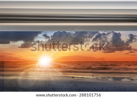 Sunshine over seascape through window with rolled up curtain