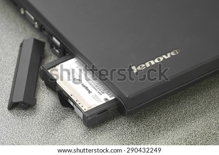 Bangkok, Thailand - May 9, 2015: Seagate HDD partially pop out of black Lenovo laptop slot over working desk