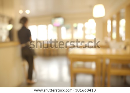 Abstract blurry restaurant with blurry back of waitress stand watching TV