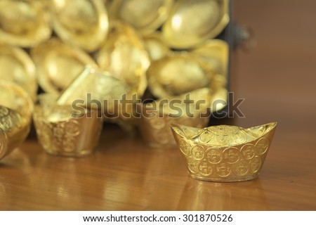 Abstract closeup of tilted treasure box with chinese style gold bar leaking out. The chinese words are crafted into gold with meaning of good fortune, best of luck, and good health.