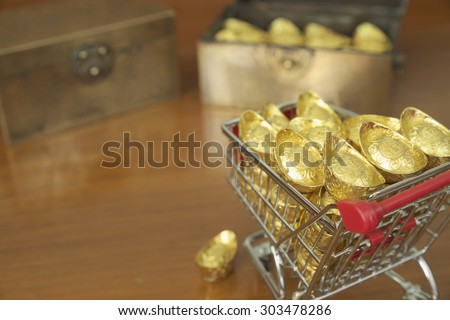 Abstract closeup concept of gold treasuring into chest by pushcart with a gold drop on its\' side. The chinese words are crafted into gold with meaning of good fortune, best of luck, and good health.