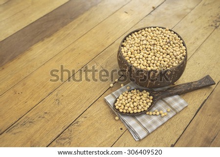 Large copyspace of wooden bowl filled with full size yellow beans and a spoonful of bean over napkin on top of wooden table