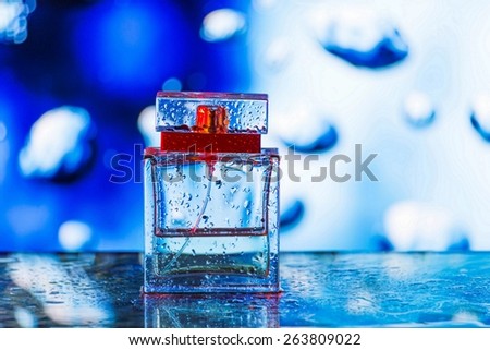 Square perfume bottle on blue, white and red background with waterdrops