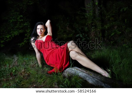a beautiful caucasian woman with dark hairs lying on an old tree log in wilderness