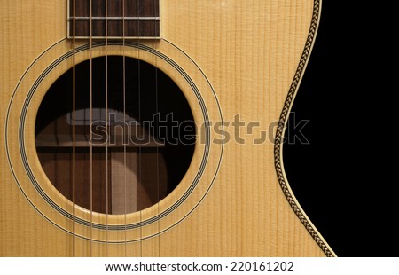 Close up of a guitar body with sound-hole, fret-board, and strings.
