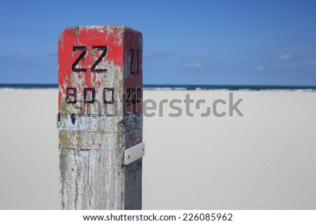 wooden pole number 22 on a beach, North Sea, island Ameland, Netherlands
