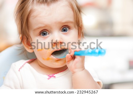 little girl feeding from a spoon on blue chair