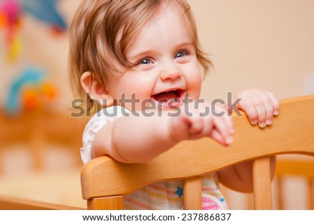 cheerful little girl standing in the crib at home