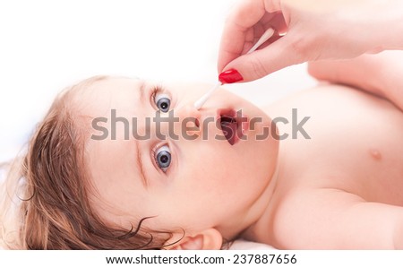 cleaning the nose a little child with a cotton swab