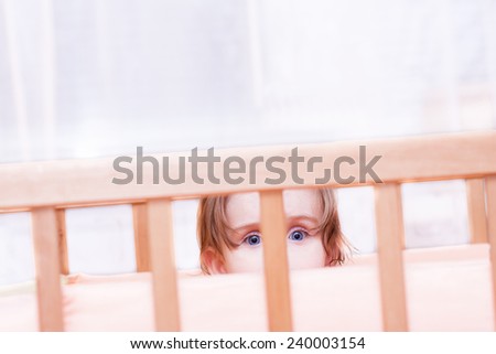 cheerful little girl sits in the crib at home