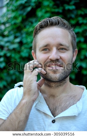 Handsome young man scratching his beard outdoor