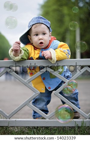 The child costs near a fence.
