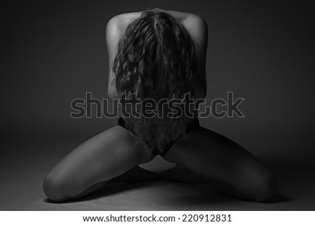 Black and white photo of sitting young woman with head down