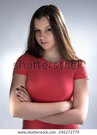 Photo of cute brunette young girl with arms crossed on gray background