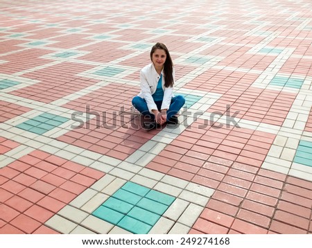 Photo of the young woman sitting on the paving slab