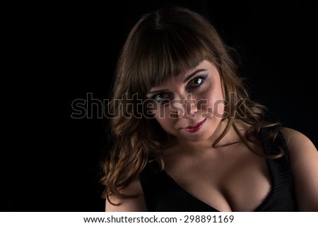 Photo of young brunette curvy woman on black background