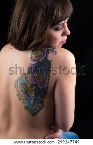Image of woman, head down, tattoo owl, from back on black background