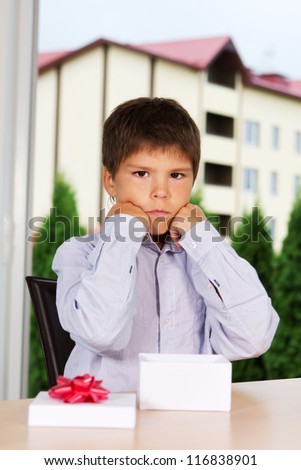 Portrait of young kid sitting sad near empty box