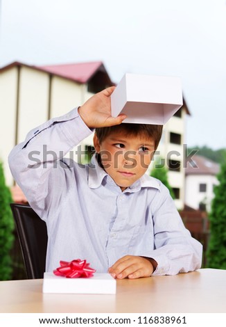 Portrait of young kid sitting sad near empty box
