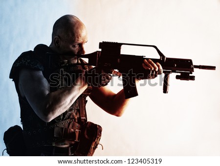 Portrait of army man posing in studio in uniform with gun