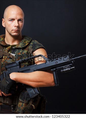 Portrait of army man posing in studio in uniform with gun