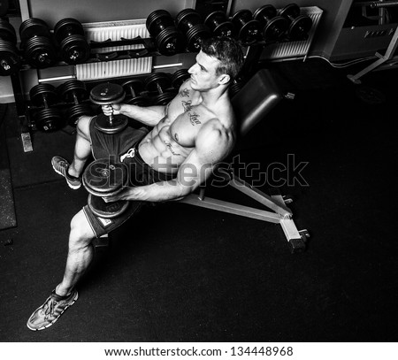 Black and white image of bodybuilder who is having work out with dumbbells