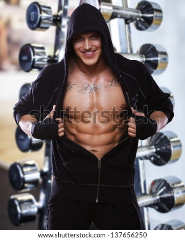 Image of muscle fighter posing in front of dumbbells
