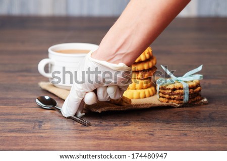 Gloved hand taking a spoon and cup with cookies