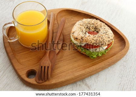 Orange juice and a sandwich on a wooden board