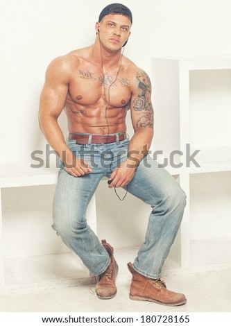 Image of guy who is wearing jeans, boots, cap and holding his mp3 player