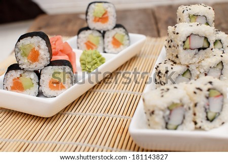 Two sushi sets on plates on a bamboo mat