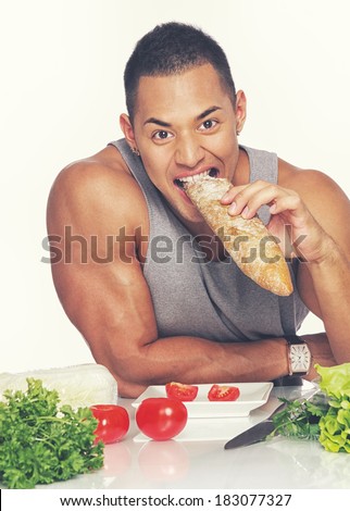 Portrait of muscle man eating bread on the kitchen