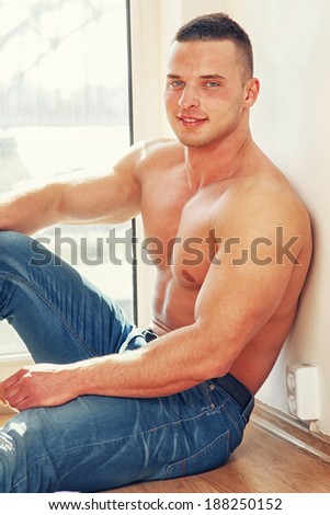 A man with no shirt sitting on the floor