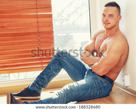 Fit guy with bare chest by the window