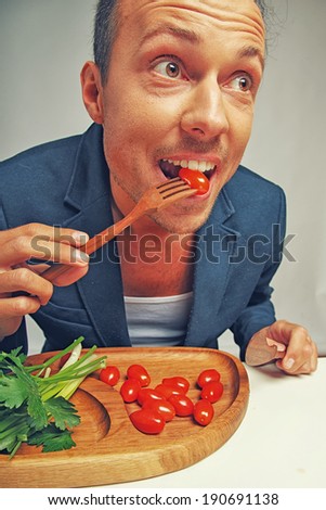 A happy man eating some tomatoes