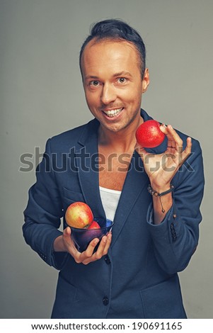 A happy man in a jacket holding apples