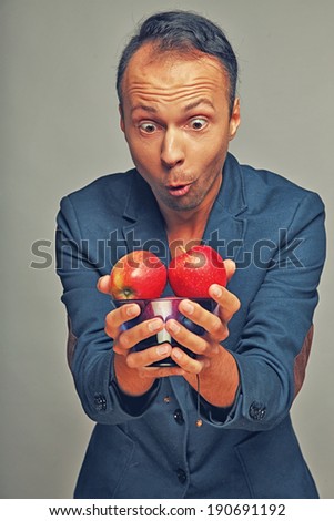 A man wearing a jacket holding apples