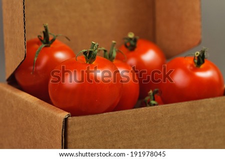 red small tomatoes close up in brown box