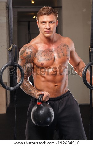 A serious tattooed man holding a 24kg weight